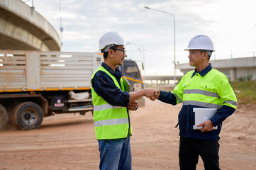 Construction engineers shaking hands at road construction site, showing teamwork, cooperation, agreement, and professional collaboration during infrastructure project.
