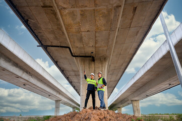 Civil engineers inspect elevated highway structure at infrastructure construction site. Supervise new road construction, structural inspection, construction work in Thailand Asia.