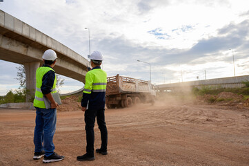 Construction engineers supervise dump truck operation at road construction site. Inspect new road construction, civil engineer working outdoors, infrastructure development in Thailand Asia.