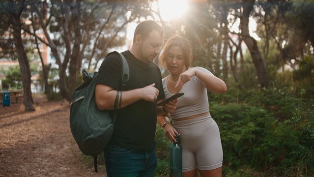 Couple hiking, navigating with smartphone app, exploring nature