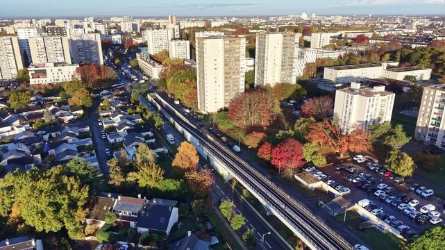 Panorama drone view of apartment buildings with parked cars along 'La Poterie' metro traffic in autumn foliage, Rennes, Brittany, France
