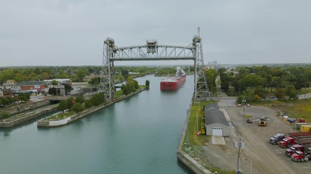 A drone shot captures the Port Colborne Clarence Street Bridge raised, with a giant laker boat going through the canal.
