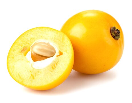Ripe nance fruit halved showing seed on white surface