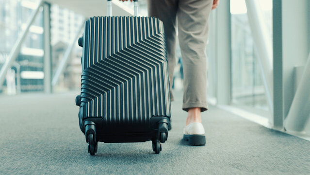Person, legs or travel with suitcase in airport for business journey, work trip or commute. Back view, employee or traveler with luggage for international boarding, corporate visit or job opportunity