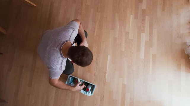 A man gets angry while trying to clean a floor stain, using the wrong cleaner and throwing the cloth in frustration.