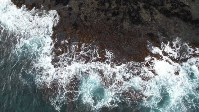 Sea waves crash against the rocks, top view