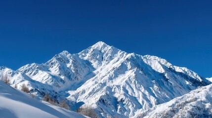 Majestic snow-covered mountains rise against a bright blue sky, showcasing winter's beauty and tranquility in a serene landscape.