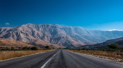 Naklejka premium Awesome photo of road leading to the mountains on a sunny day with clear blue sky.