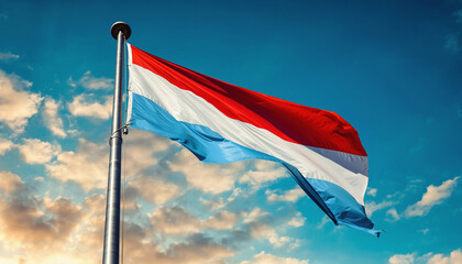 A vibrant Luxembourgish national flag proudly waves against a clear blue sky with soft clouds, symbolizing national identity and freedom for the nation