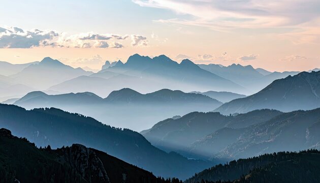 A scenic view of multiple mountain ranges receding into the distance, bathed in the soft light of sunrise.