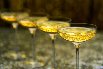 Many glasses of champagne in a line, selective focus. Lots of champagne in a  coupe glasses.