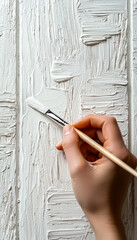 Applying white paint with a brush to textured wooden surface