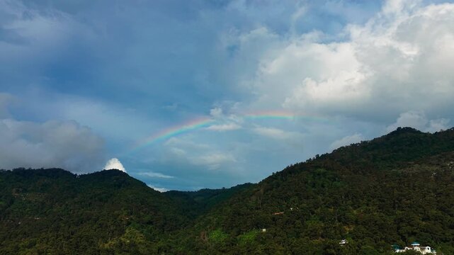 Spectacular Aerial Drone Shot of Double Rainbow Arching Over Lush Green Mountain Landscape After Rainfall
