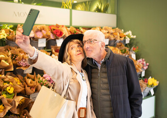 Senior couple sharing happy romantic moment taking a selfie in a flower shop