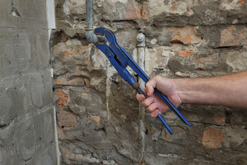 Home renovation, plumber fixing or replacing old pipes in a bathroom, using adjustable wrench tool, closeup of hand with tool