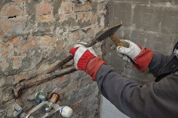 Home renovation, plumber replacing old pipes in a bathroom, using hammer and chisel, closeup of hands with tool