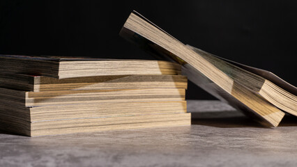 Books stacked horizontally with one volume lifted open, revealing natural paper tones and dramatic shadows, ideal for themes of research, reading, and education.