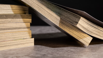 Detailed shot of open and stacked books in warm studio lighting, highlighting paper grain and creating a cozy academic mood suitable for study or literature concepts.