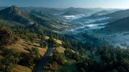 Aerial View of Highway Through a Valley Covered in Morning Mist with Rugged Mountains