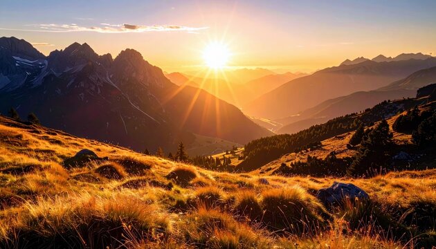 A breathtaking sunrise casts golden light across a rugged mountain range, highlighting rolling hills covered in dry grass and distant valleys. - Powered by Adobe