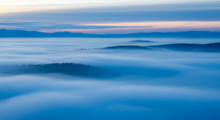 Breathtaking aerial view of rolling hills and forests submerged under a thick blanket of blue fog or low clouds, with mountain ridges peaking through.
