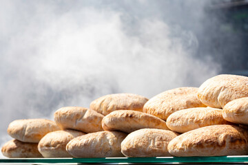 View of breads in the street shop. Small loaves, rolls. Smoke from the grill in the background.