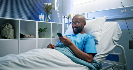 Medical, smile or black man in hospital with phone, video streaming or message update on surgery. Healthcare, happy and patient in clinic with tech, digital scroll or online communication in recovery