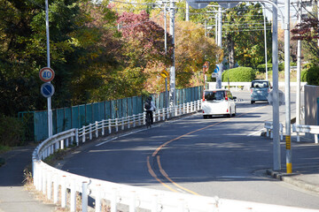 秋の朝の街のカーブの道路と自転車を乗る若い男性の姿