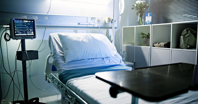 Empty bed, hospital and room for healthcare, icu and EKG screen for rehabilitation at night. Clinic interior, medical equipment and monitor with ECG, iv drip and healing with wellness in facility