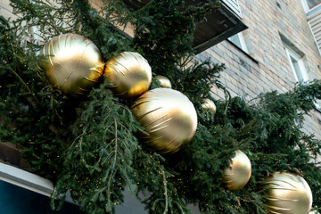 Christmas street decorations. Huge golden balls among the spruce branches at the top of the shop window.