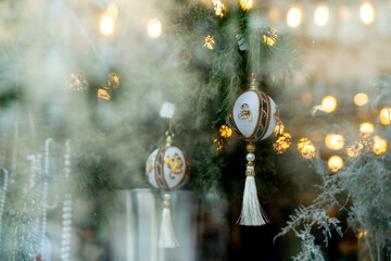 Christmas street decorations. Beautiful Christmas balls with tassels hanging on the branches of a fir tree in a shop window.