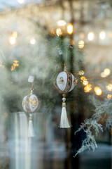 Christmas street decorations. Beautiful Christmas balls with tassels hanging on the branches of a fir tree in a shop window.