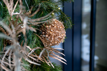 Christmas street decorations. Gilded plants among the branches of spruce, fir and pine, decorating the entrance to the store.