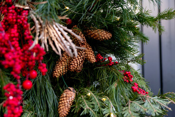 Christmas street decorations. Cones, red berries, gilded plants among the branches of spruce, fir and pine, decorating the entrance to the store