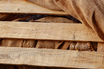 textured brown burlap fabric draped over a weathered, beige wooden slat