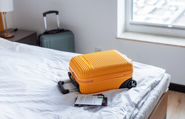 Orange suitcase on hotel bed welcoming travelers arrival
