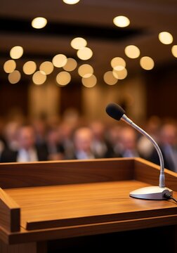 Formal presentation setting with a lectern and microphone in sharp focus, anticipating a speaker's arrival