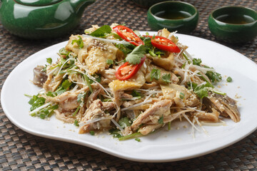 Spicy shredded chicken, arranged on a fan-shaped white porcelain plate, is placed on a placemat.