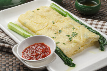 A rectangular white porcelain plate holds a Hong Kong-style egg pancake on a placemat.