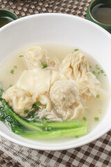 Fototapeta premium Wontons in a white porcelain bowl were placed on a placemat.