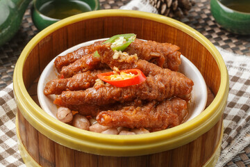 Steamed chicken feet in a bamboo steamer are placed on a tablecloth.