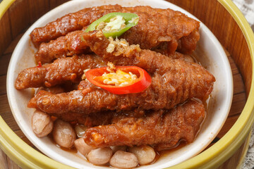 Steamed chicken feet in a bamboo steamer are placed on a tablecloth.