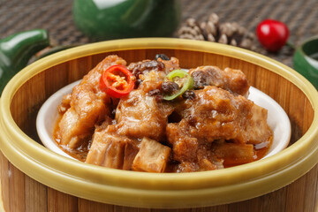 Steamed chicken feet in a bamboo steamer are placed on a tablecloth.