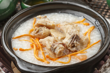 A black clay pot of cordyceps flower and pork rib congee was placed on a tablecloth.