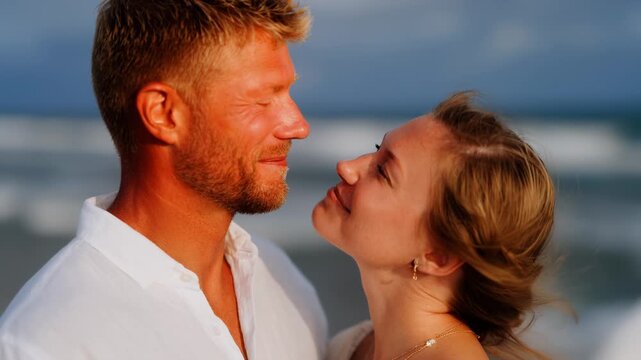 Couple enjoys a romantic moment on the beach during sunset while sharing smiles and sweet glances - Powered by Adobe
