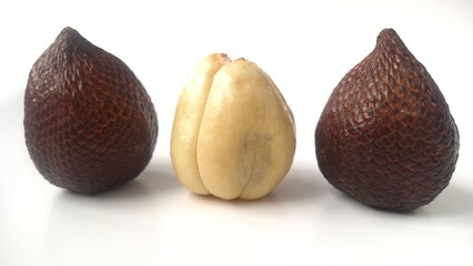 Three salak or snake fruit. Three salak fruits (Salacca zalacca) displayed against a plain background. Each fruit features a distinctive reddish-brown scaly skin, resembling snake scales