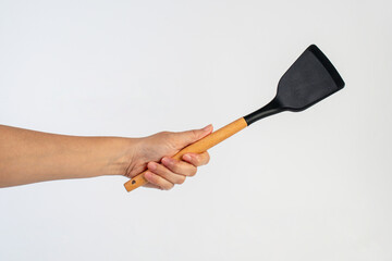 Hand with Black plastic kitchen spatula, kitchenware for cooking on white background.
