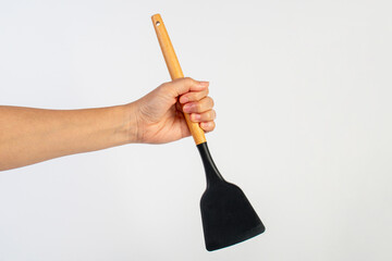 Hand with Black plastic kitchen spatula, kitchenware for cooking on white background.