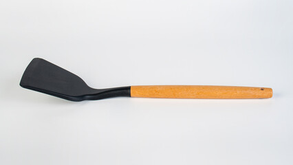 Hand with Black plastic kitchen spatula, kitchenware for cooking on white background.