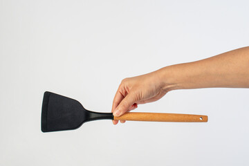 Hand with Black plastic kitchen spatula, kitchenware for cooking on white background.
